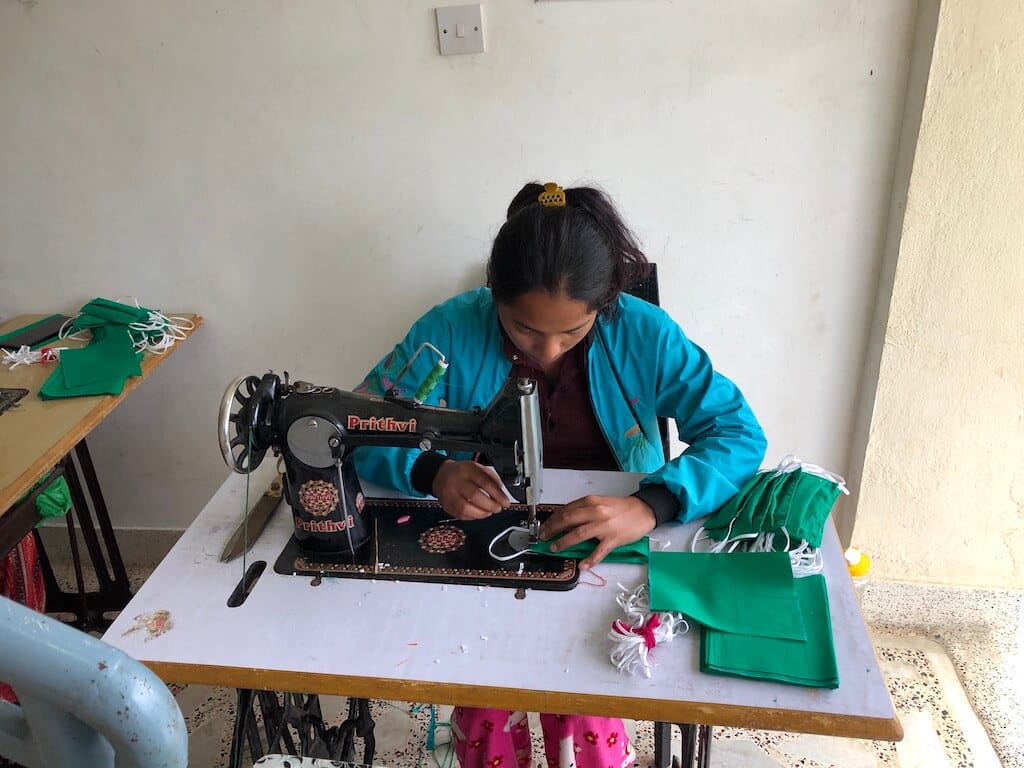 A volunteer sows masks for children in Nepal to help stem the spread of COVID-19