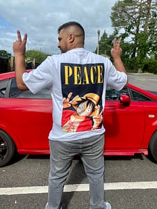 Billa Nanra gives the peace sign with his hands while showing the back of his T-shirt which has the word 