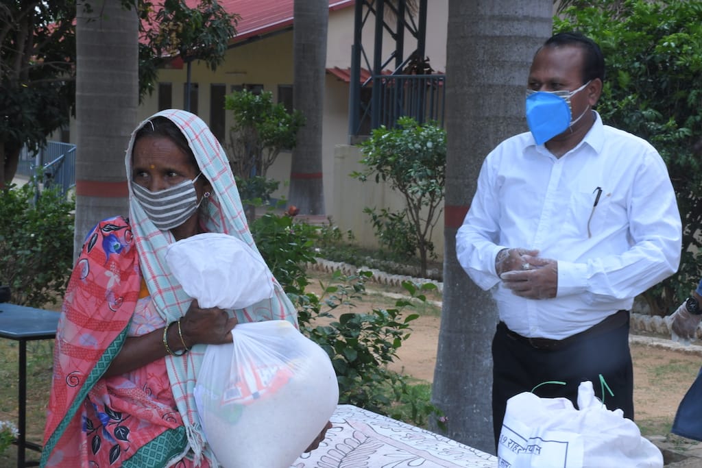 Uma pessoa com deficiência pega uma sacola de comida na unidade Alimento para Todos na Índia