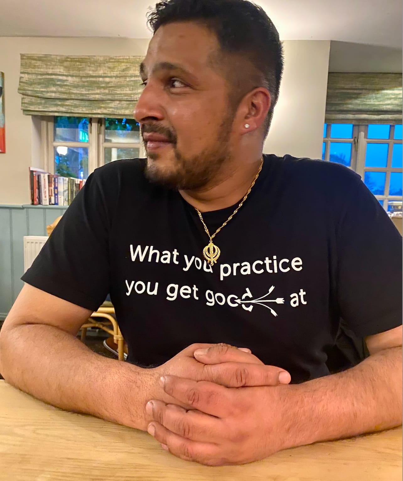 Billa Nanra wears a black T-shirt with a quote from Prem Rawat: "What you practice you get good at."