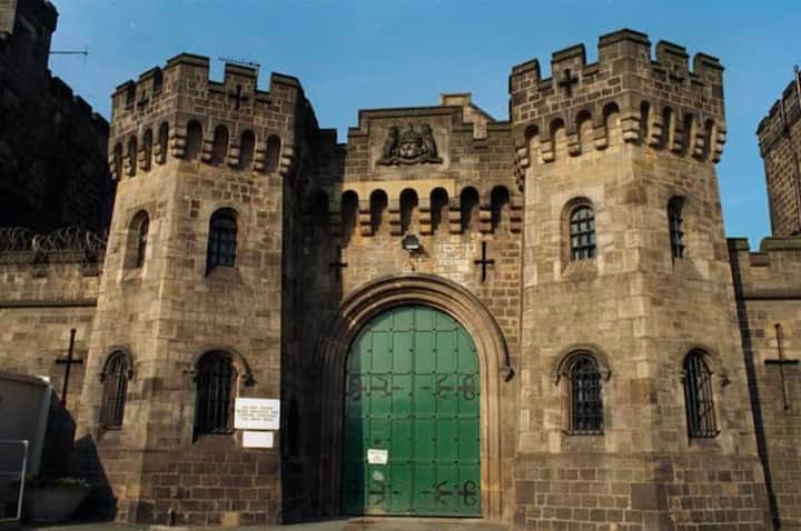 The front entrance to His Majesty's Prison in Leeds, England. The old stone building resembles a castle and features a green, iron front door.