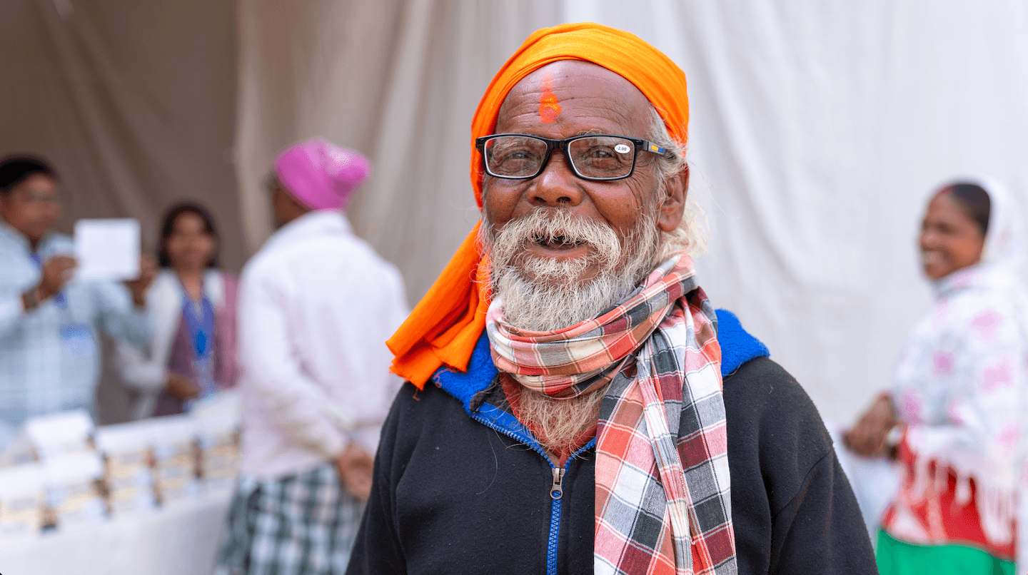 TPRF Eye Clinic Chhattisgarh India-Jan 31 & Feb 1-happy man with glasses Elderly man in bright orange headscarf smiles after receiving prescription glasses at The Prem Rawat Foundation's eye clinc in Chhattisgarh in India.