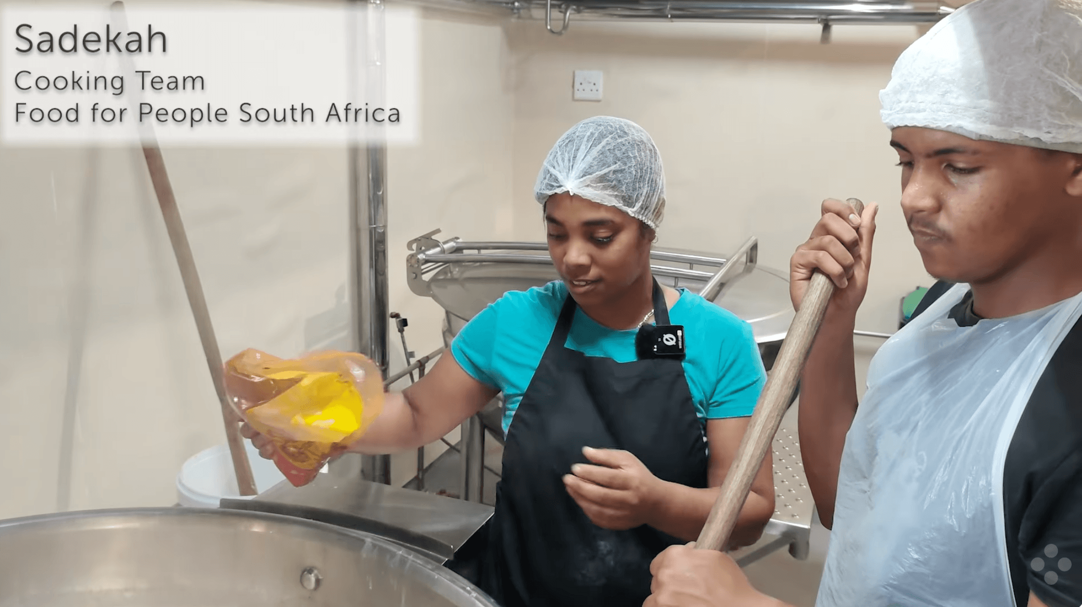 A young woman and young man prepare a nutritious meal in a huge steel cooking pot in the renovated Food for People kitchen, Cape Flats, South Africa.